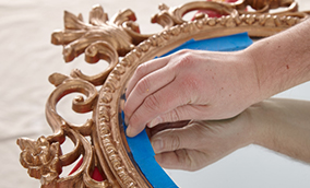 Person applying painter's tape to a mirror