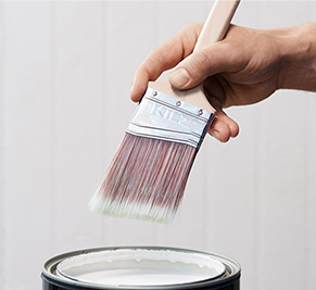 Paint brush dipping into can of promer