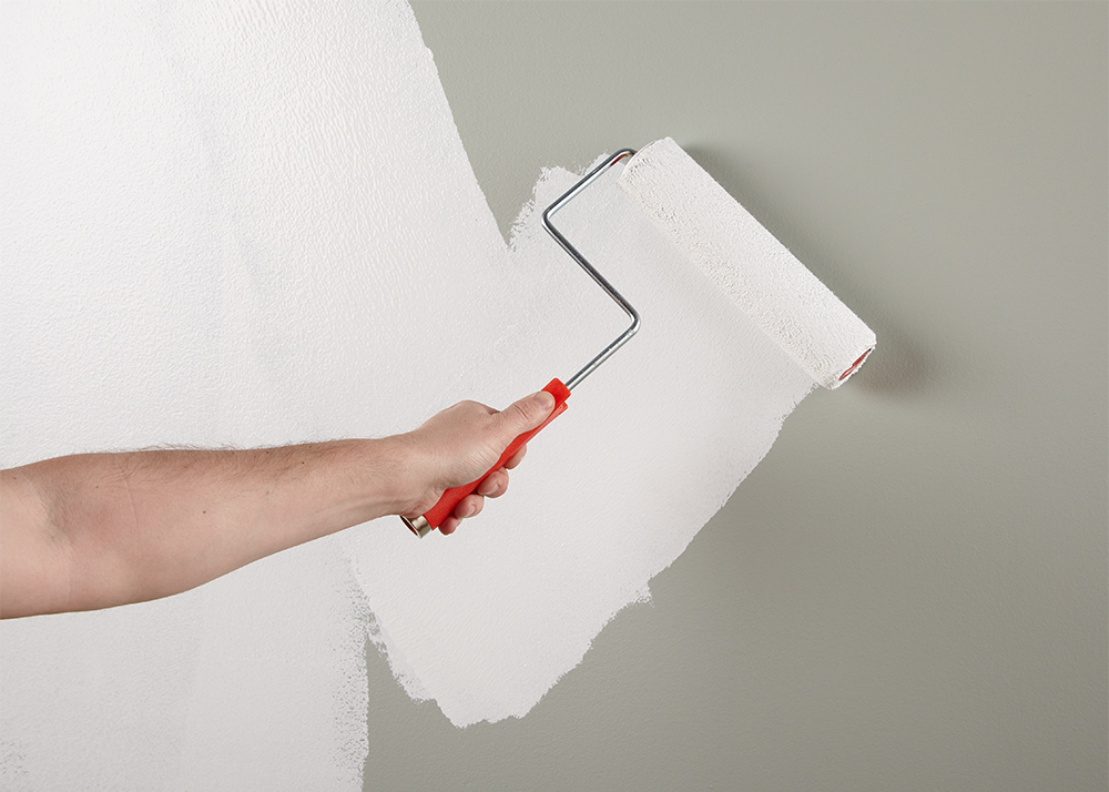 Person painting a wall white
