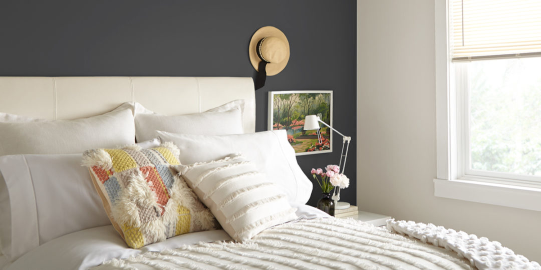 Bedroom with a Navy accent wall and a bed with white sheets and white headboard