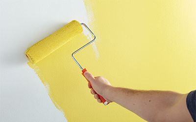 Person painting a wall yellow