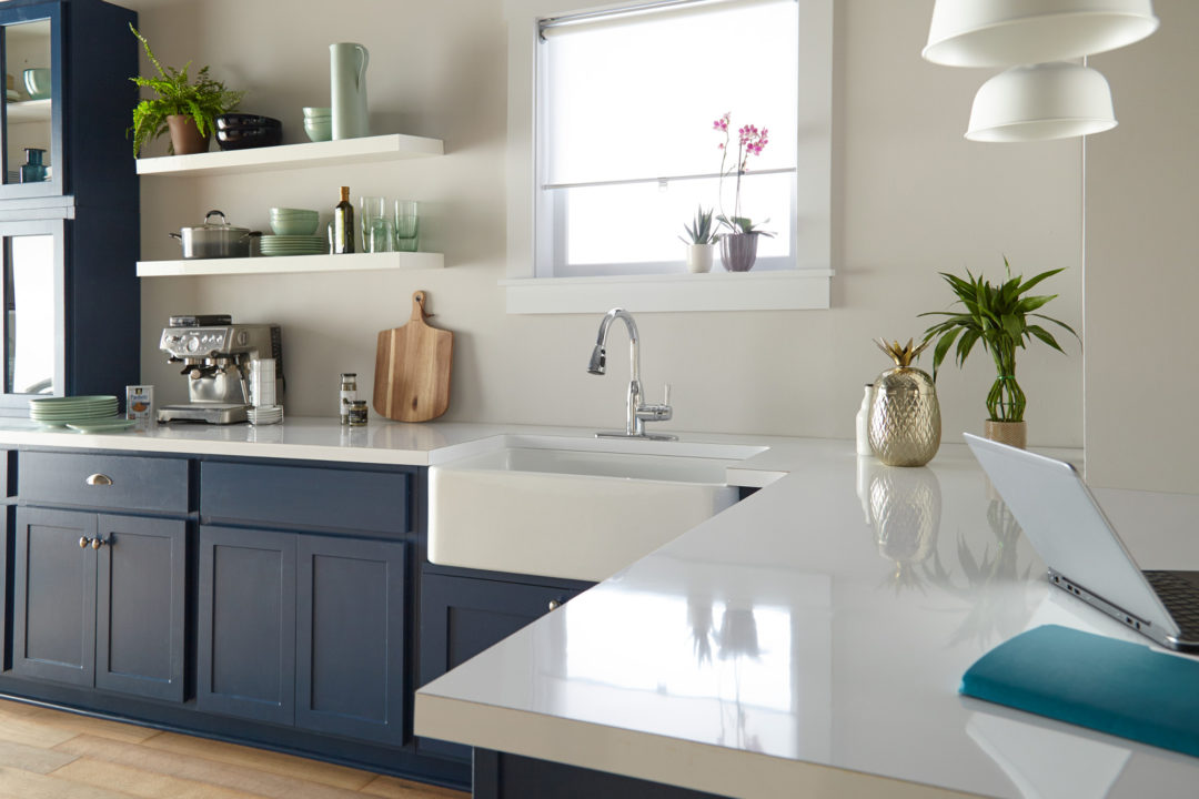 Kitchen with navy cabinets and white countertops with a large white farmhouse sink