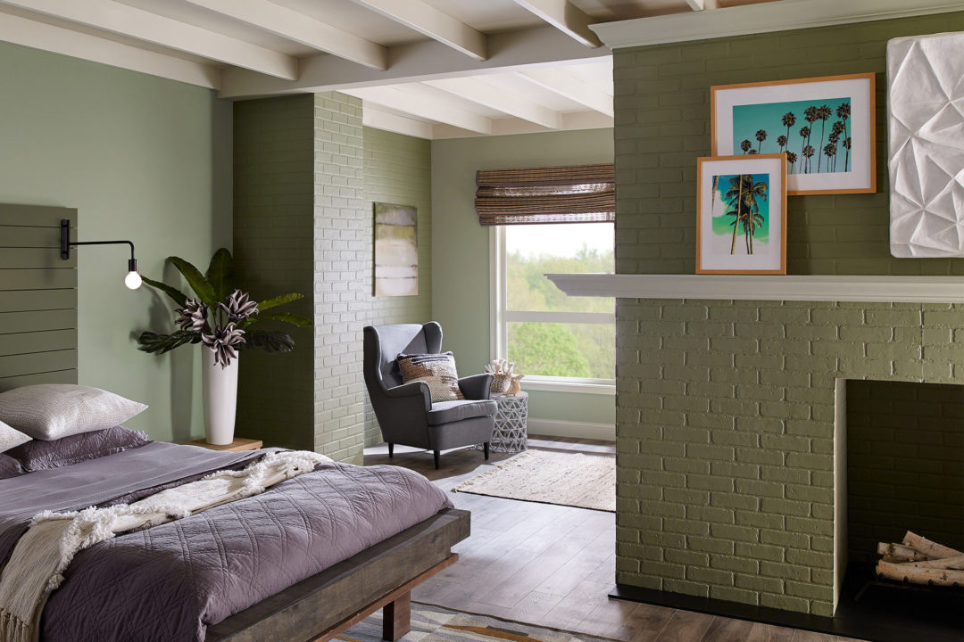 Bedroom with green walls and a green fireplace with a bed that has purple sheets