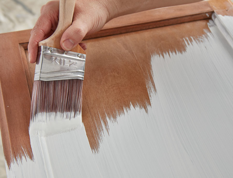 Image of hand priming a cabinet door with KILZ paint brush.