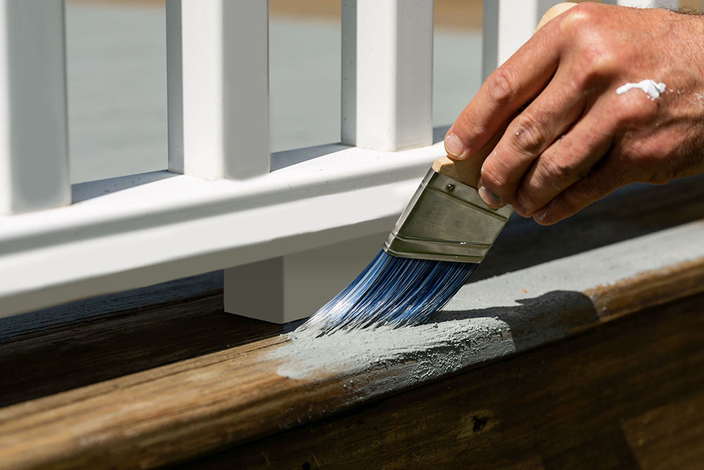 Painter applying Kilz OverArmor Texture Slate Gray with brush applicator to railing of deck