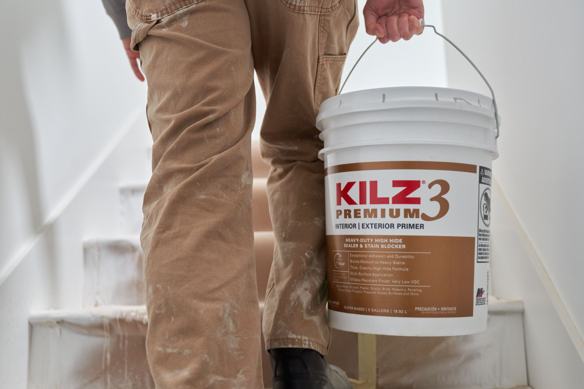Image of painter walking up stairs with a 5-gallon bucket of KILZ 3 Premium primer.