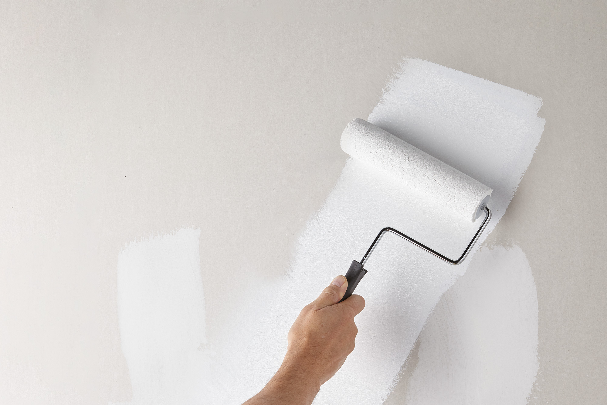 Paint Roller Covering Cream Walls with White Primer.