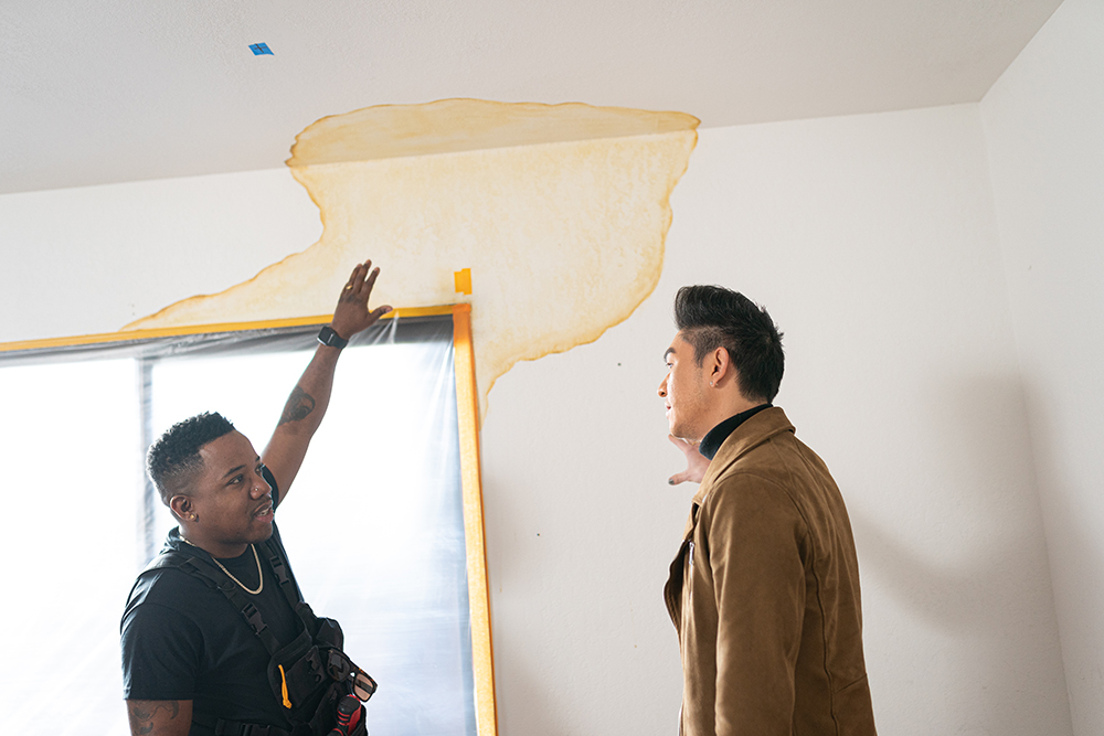 Jared Foster and Jason Lai pointing at water stain