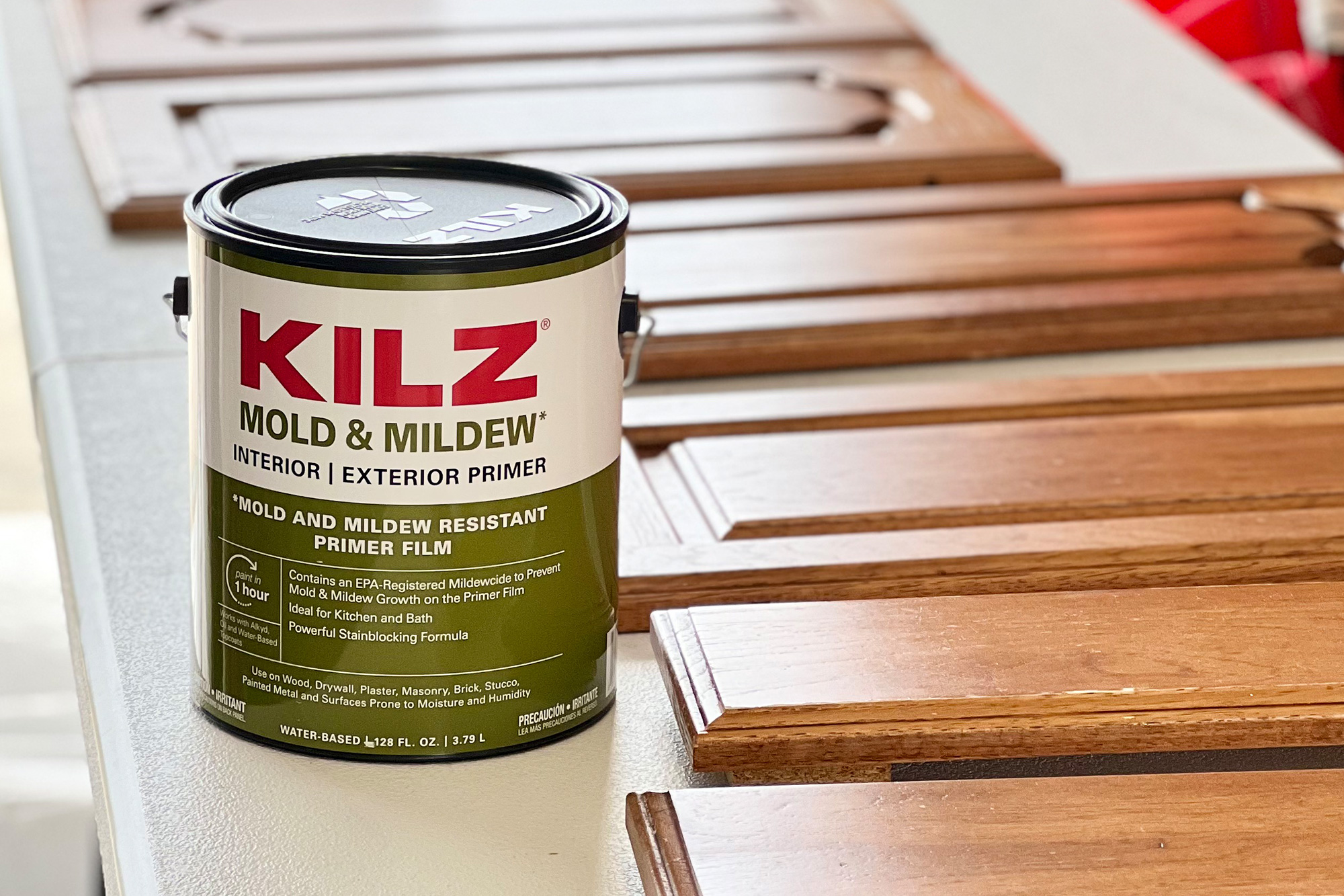 KILZ Mold & Mildew 1 gallon can next to wood cabinet doors on a table.