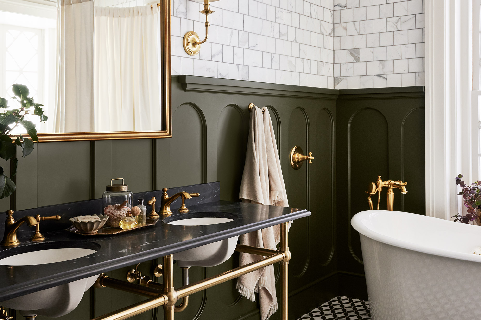 Bathroom image, showing the sink, white tiles on the upper part of the wall, and using the interior paint color Step Stool green from Magnolia Home by Joanna Gaines on wood paneling below.