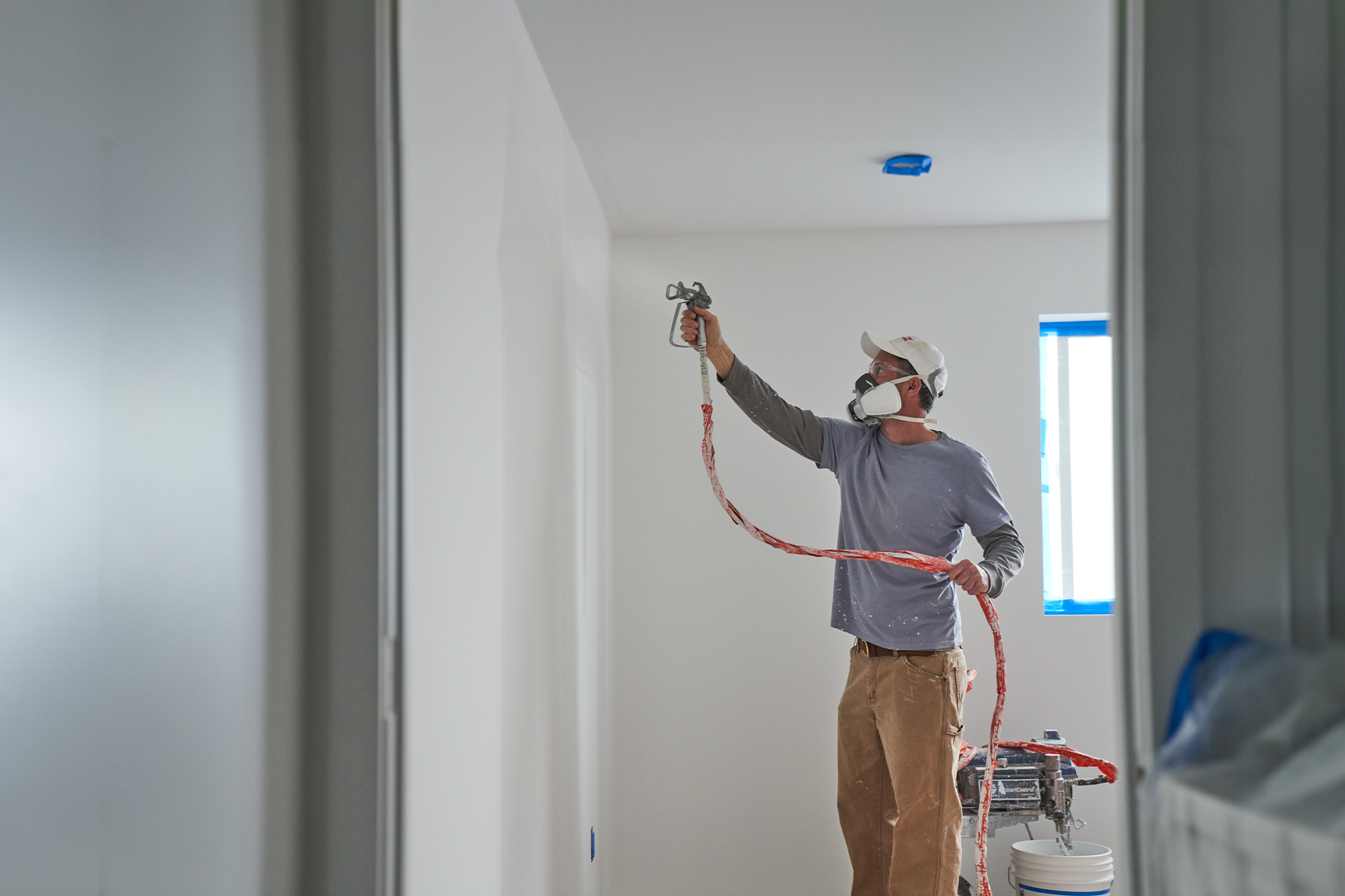 image of painter spraying primer on the wall.
